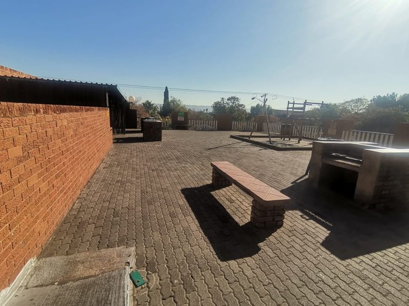 Spacious outdoor patio area featuring brick paving, a built-in braai, and perimeter walling, suitable for communal or private outdoor entertainment.