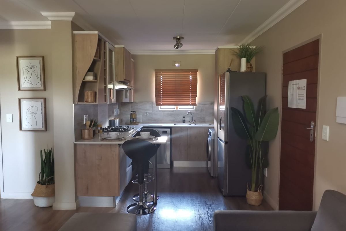 A well-maintained kitchen featuring modern wood-finish cabinetry, a gas hob, integrated extractor, and laminate flooring, offering a functional and contemporary cooking space.