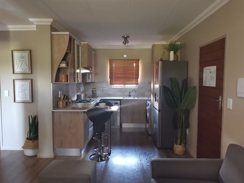 A well-maintained kitchen featuring modern wood-finish cabinetry, a gas hob, integrated extractor, and laminate flooring, offering a functional and contemporary cooking space.
