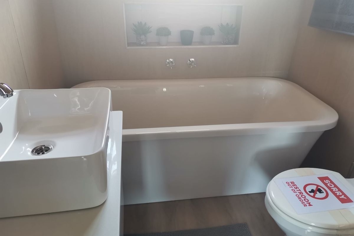 Modern bathroom featuring a freestanding bathtub, vessel sink with wall-mounted faucet, and a convenient recessed wall niche for storage.