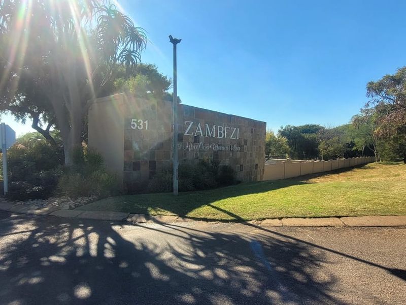 Street view of the Zambezi Retirement Village entrance featuring a stone-clad signage wall and well-maintained landscaped verge.