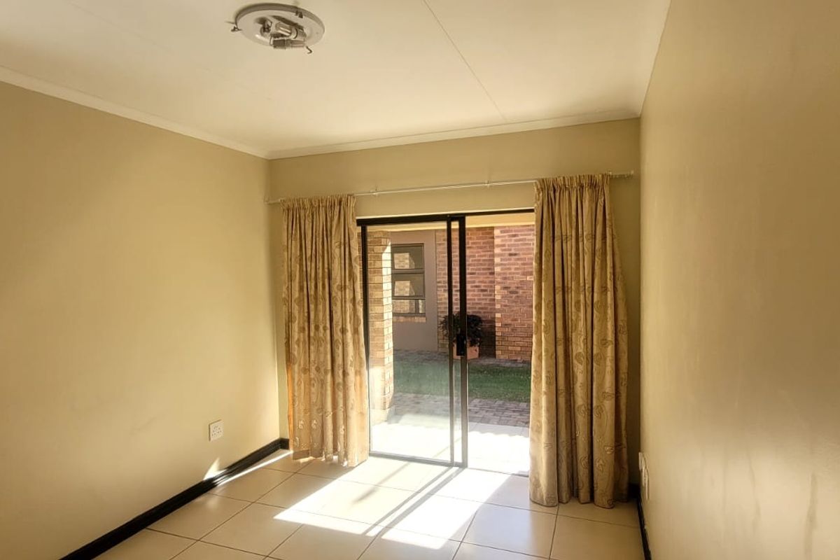 An empty bedroom featuring neutral walls, ceramic floor tiles, and a sliding glass door providing direct access to an outdoor patio area.