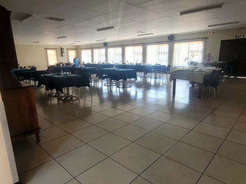 Spacious communal dining or clubhouse area featuring tiled flooring, large windows for natural light, and essential safety equipment.