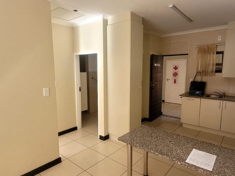 An open-plan living and kitchen area featuring tiled flooring, built-in cabinetry with granite countertops, and a functional layout suitable for retirement living.