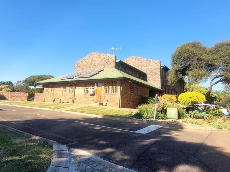 Exterior view of a face brick retirement village building featuring a pitched roof with solar panels and surrounding landscaped grounds.