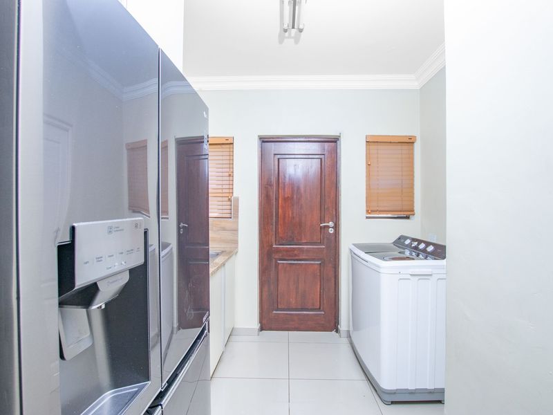 A functional laundry area featuring tiled flooring, a solid wooden door, and venetian blinds, providing a clean and practical utility space.