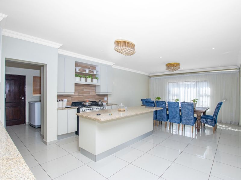 Spacious open-plan kitchen and dining area featuring a central island, granite countertops, modern cabinetry, and polished tile flooring throughout.
