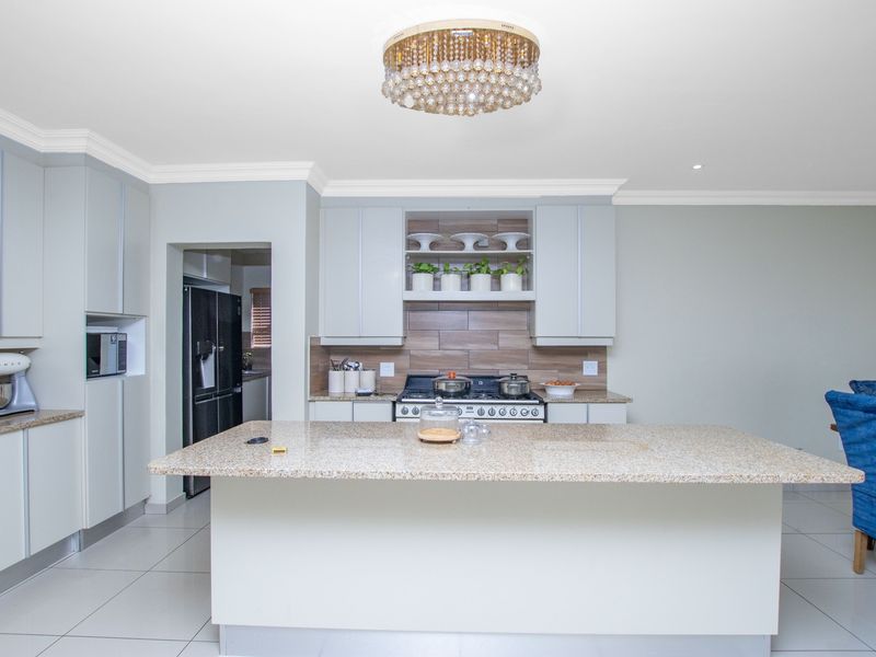 Modern kitchen featuring a central island with granite countertops, ample built-in cabinetry, a gas stove, and elegant crown molding.
