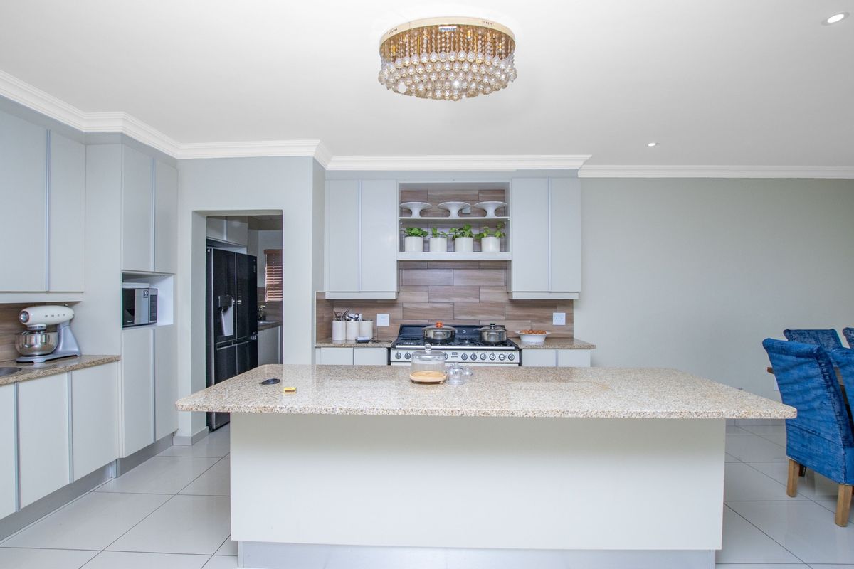 Modern kitchen featuring a central island with granite countertops, ample built-in cabinetry, a gas stove, and elegant crown molding.