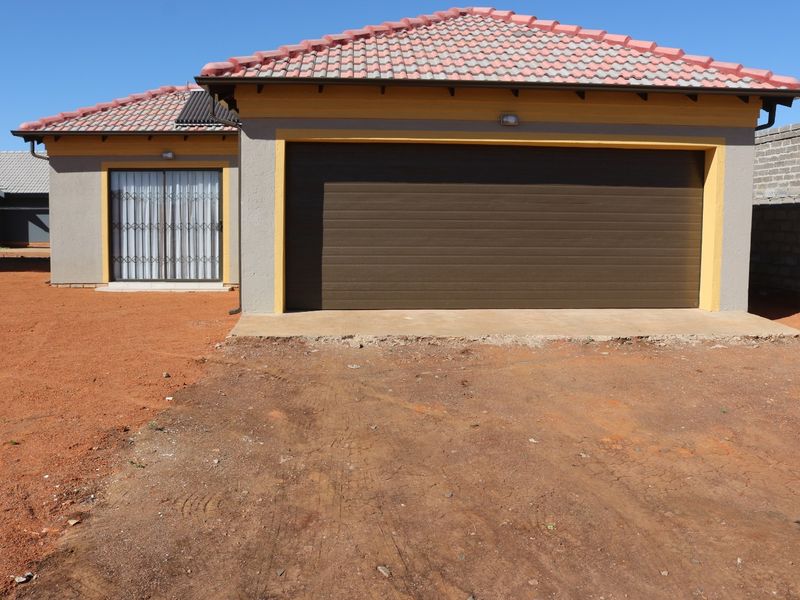 Front elevation of a residential house featuring a tiled roof, a large sectional garage door, and a sliding door entrance with security gate.