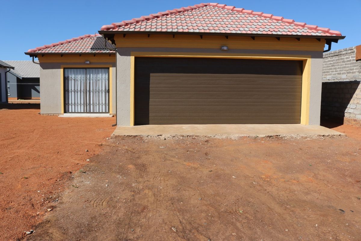 Front elevation of a residential house featuring a tiled roof, a large sectional garage door, and a sliding door entrance with security gate.