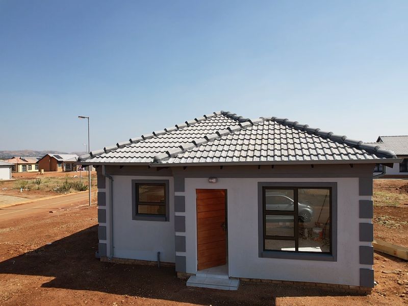 A modern single-story residential house featuring a tiled roof, plastered exterior walls with corner detailing, and aluminium window frames.