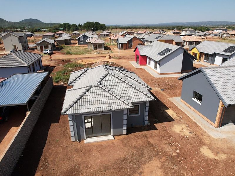 Aerial view of a residential development featuring modern detached houses with tiled roofs, solar panels, and unlandscaped garden plots.