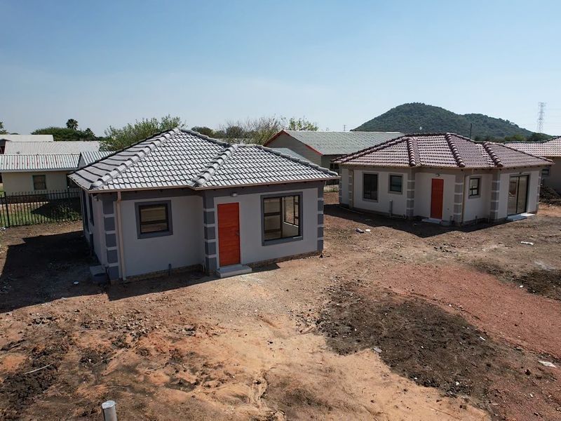 Aerial view of newly constructed residential houses featuring tiled roofs, grey exterior walls with contrasting quoins, and aluminium window frames in a developing estate.