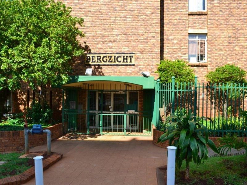 The front entrance of the Bergzicht apartment complex, featuring a face brick facade, secure metal gate, and paved walkway access.