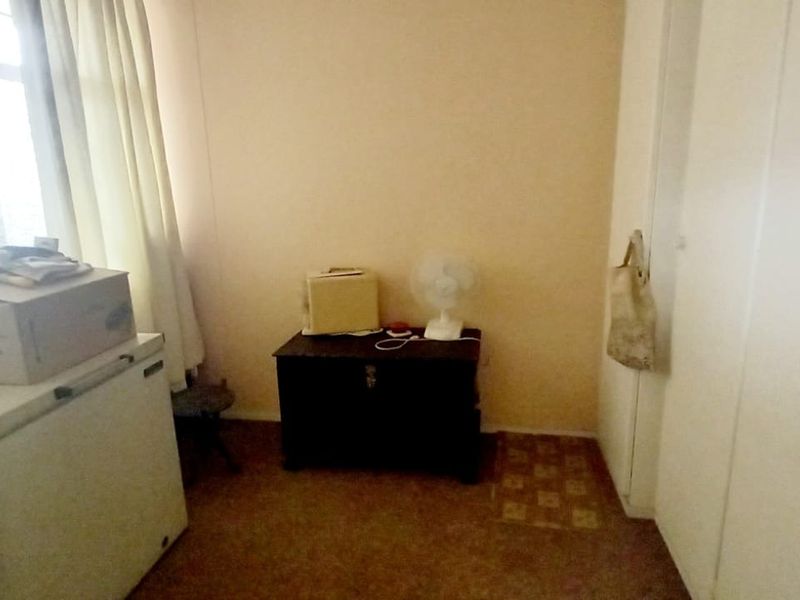 A compact bedroom featuring built-in cupboards and carpeted flooring, offering a functional space that could benefit from modern updates and cosmetic improvements.