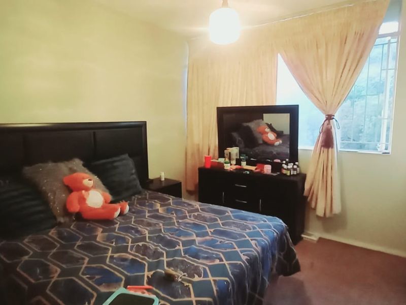 A bedroom featuring a built-in wardrobe and a window with security bars, providing a functional living space.