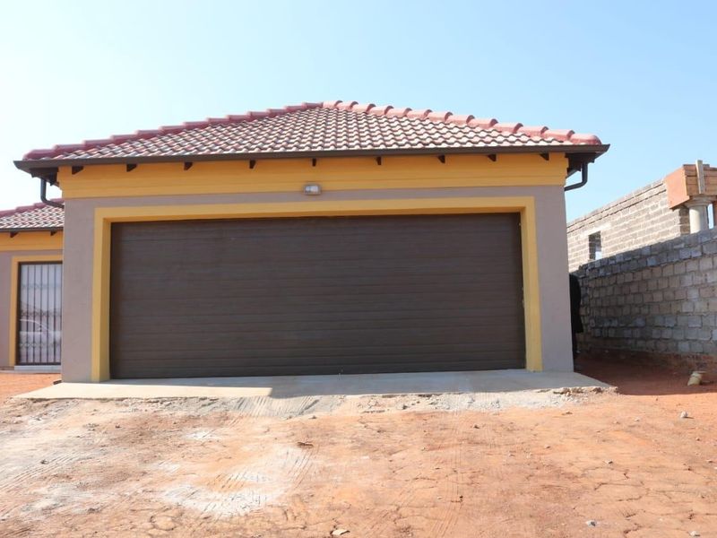 A modern single garage with a tiled roof and sectional door, featuring a security gate on the side entrance and an unfinished driveway area.