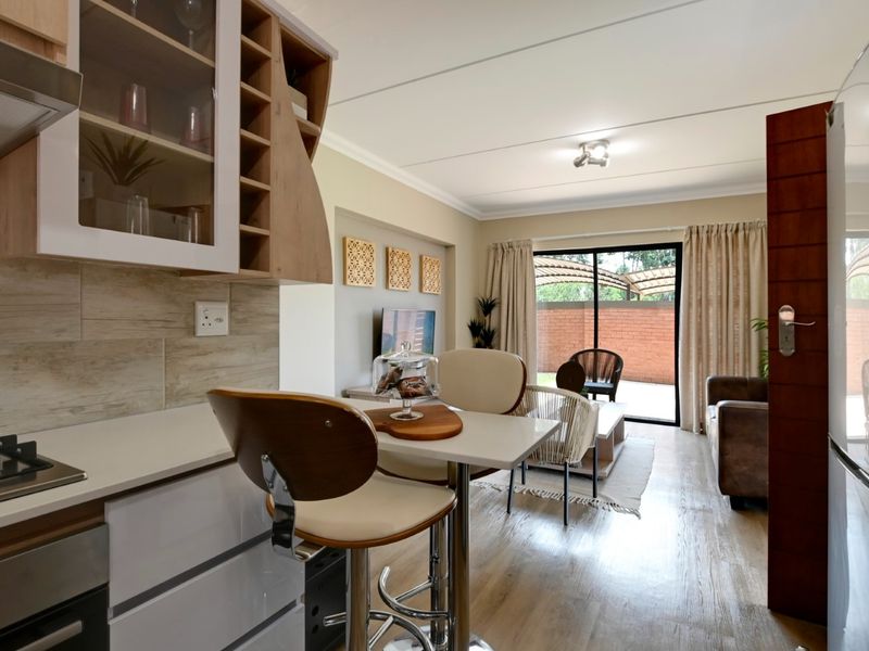 Modern open-plan kitchen and living area featuring sleek cabinetry, integrated appliances, and sliding doors leading to an outdoor patio space.