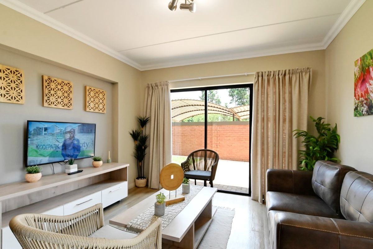 A well-maintained living room featuring laminate flooring, cove molding, and a large sliding glass door providing access to the outdoor area.