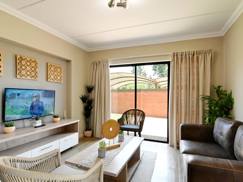 A well-maintained living room featuring laminate flooring, cove molding, and a large sliding glass door providing access to the outdoor area.