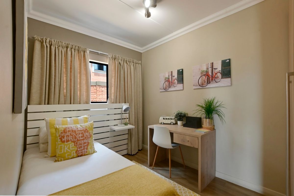 A well-maintained bedroom featuring laminate flooring, coving, and a window with neutral wall tones.