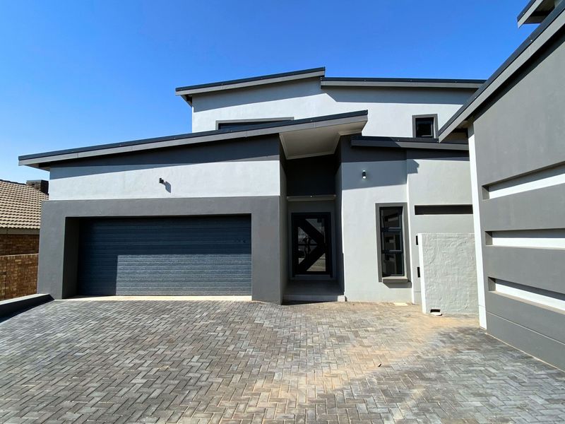 Modern double-story home exterior featuring a paved driveway, integrated double garage, and contemporary architectural design with clean lines.