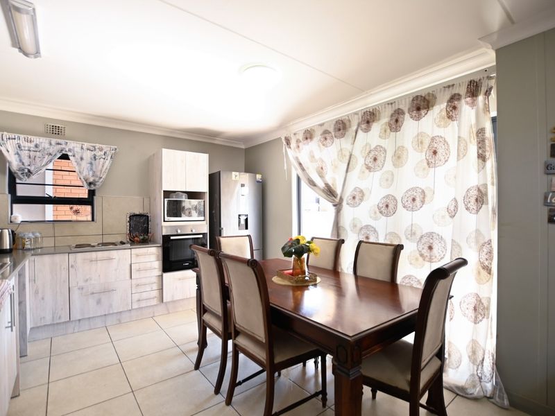 An open-plan kitchen and dining area featuring light-toned cabinetry, built-in appliances, and tiled flooring, creating a functional and cohesive living space.
