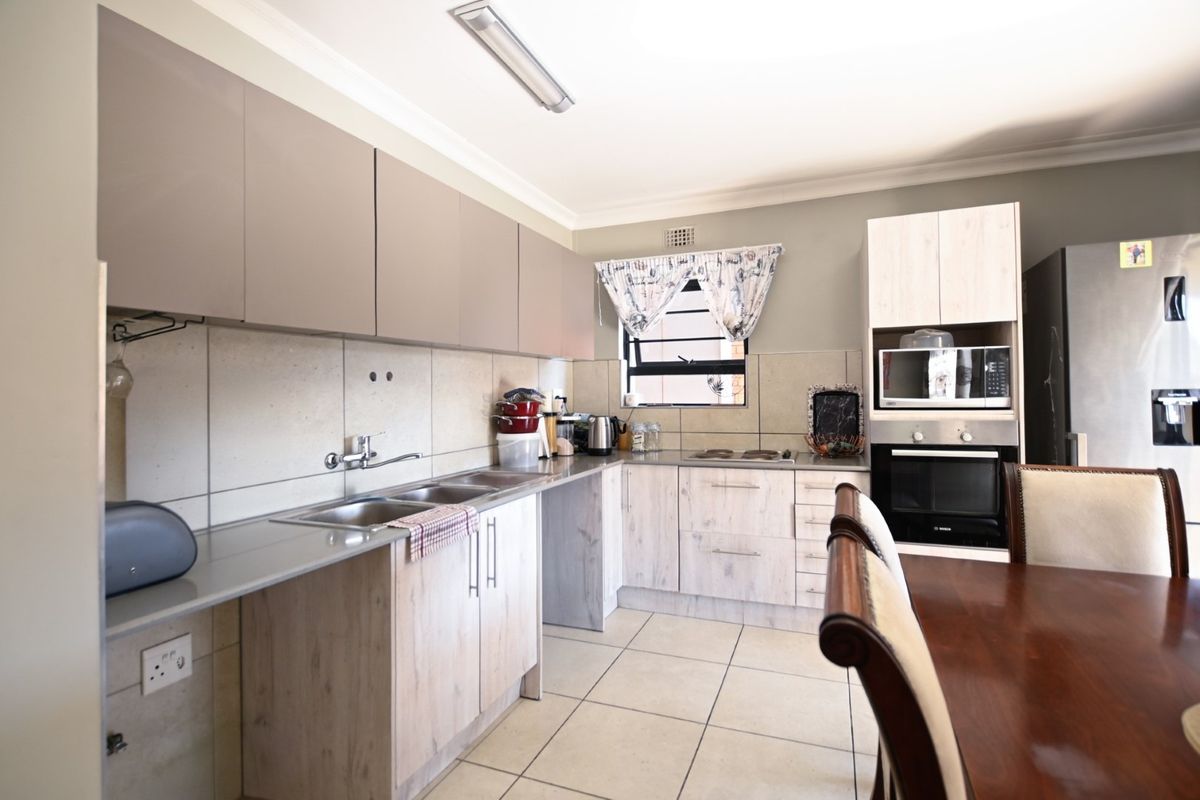 A functional kitchen featuring light wood-look cabinetry, a double sink, tiled backsplash, and built-in oven and microwave appliances.