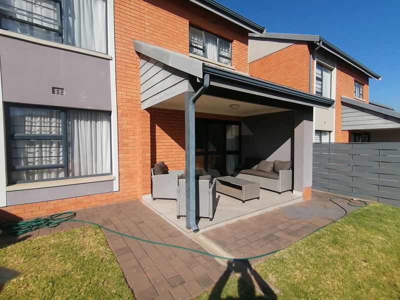 A covered patio area featuring tiled flooring and brick exterior walls, providing direct access to the interior through sliding glass doors.