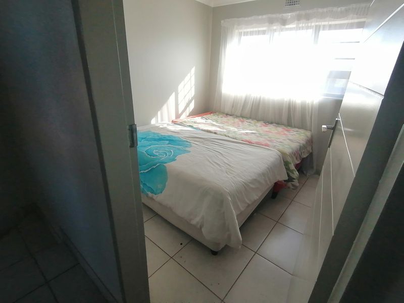 A compact bedroom featuring tiled flooring and a window, providing natural light.