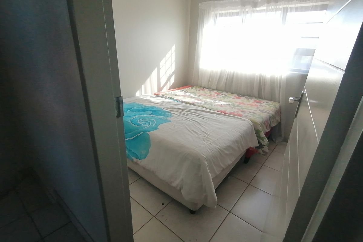 A compact bedroom featuring tiled flooring and a window, providing natural light.