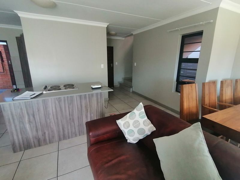 Open plan living area featuring a kitchen island with integrated hob, tiled flooring, and neutral wall finishes.