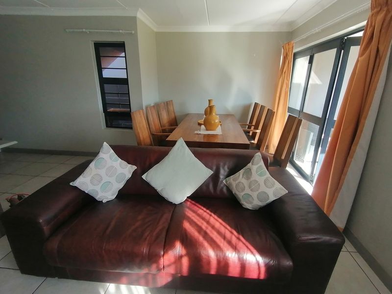 Open plan living and dining area featuring tiled flooring, coved ceilings, and large sliding doors providing access to the outdoor space.
