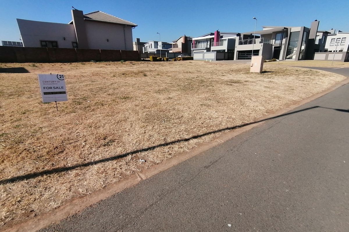 A vacant residential plot situated in a developed estate, featuring street access and nearby utility connections.