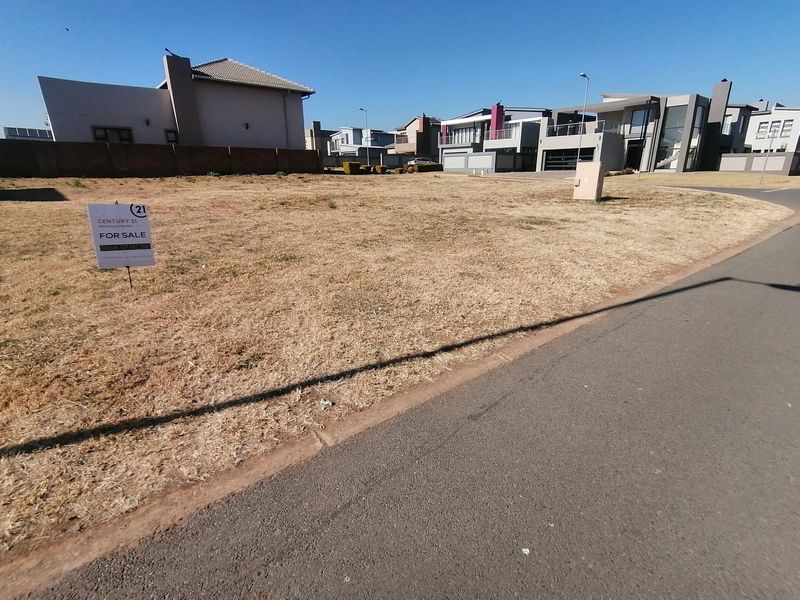 A vacant residential plot situated in a developed estate, featuring street access and nearby utility connections.