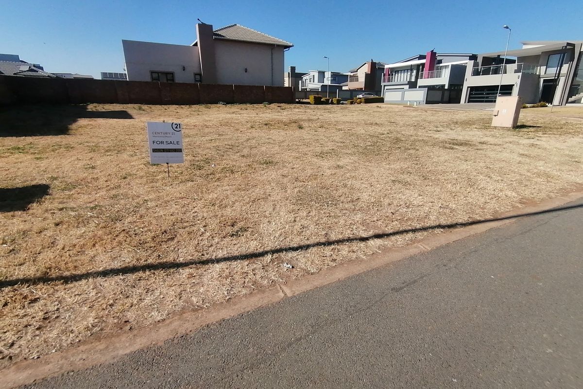 A vacant residential plot of land featuring a boundary wall and electrical connection point, situated in a developed neighborhood.