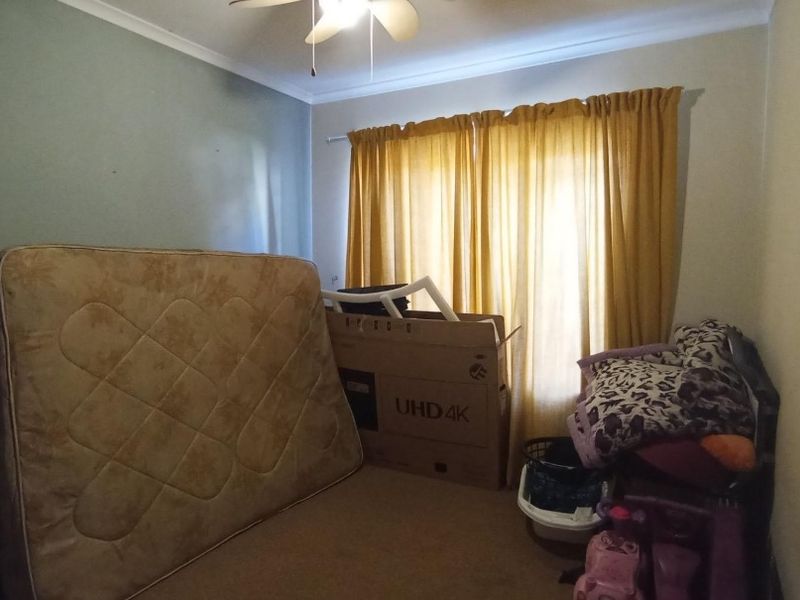 A bedroom featuring a ceiling fan and carpeted flooring, currently used for storage.