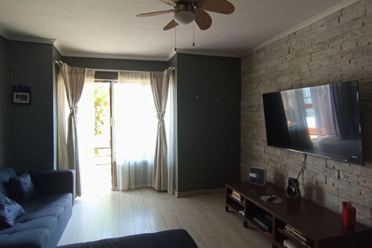 A comfortable living room featuring a textured stone accent wall, ceiling fan, and sliding glass doors that provide access to the outdoor area.
