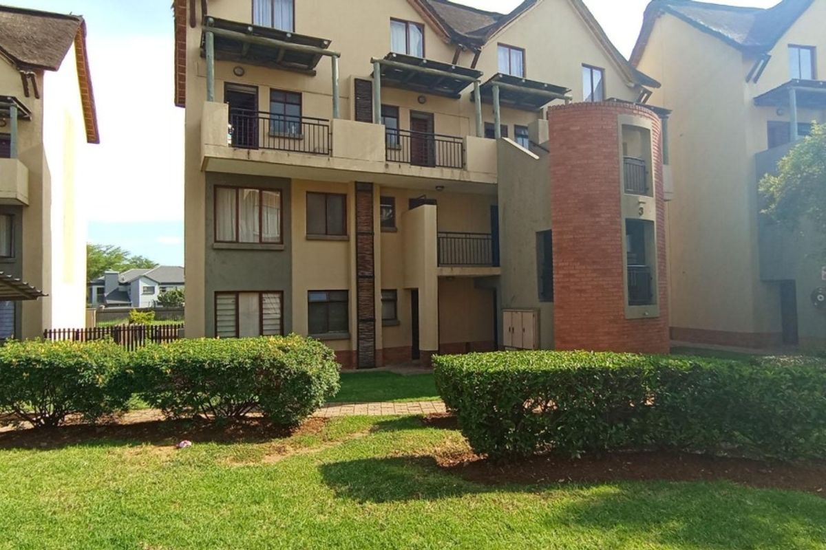 Rear view of a multi-story townhouse complex featuring private balconies, brick architectural detailing, and well-maintained communal garden spaces.
