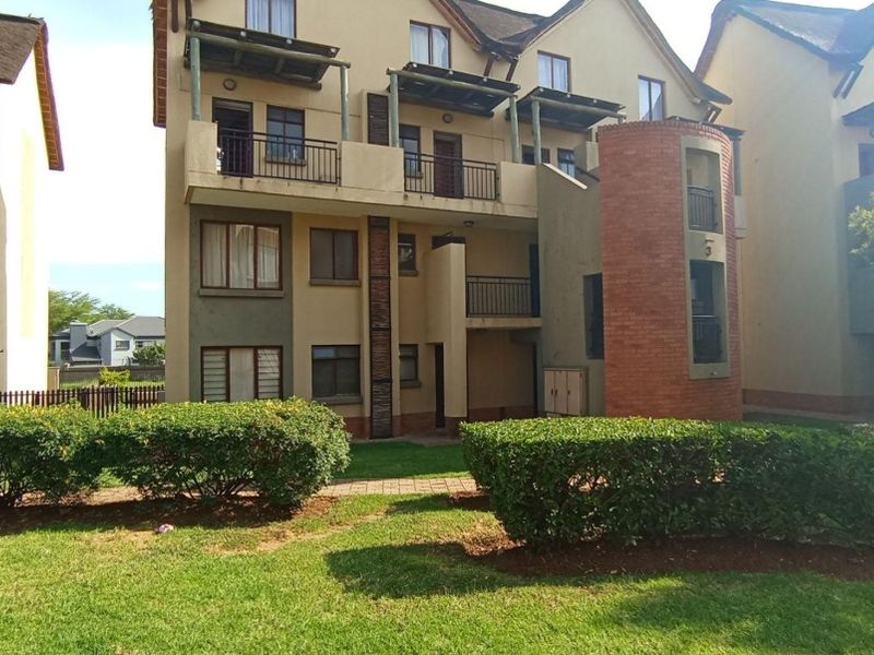 Rear view of a multi-story townhouse complex featuring private balconies, brick architectural detailing, and well-maintained communal garden spaces.