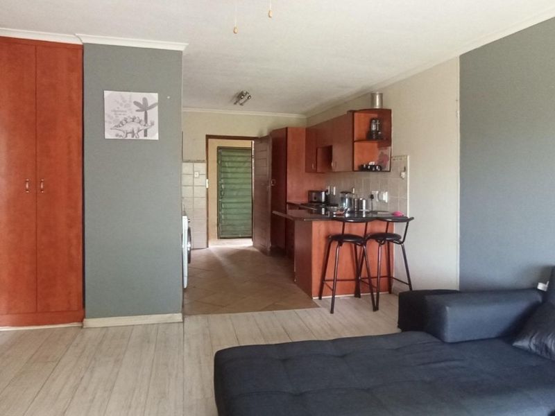 Open-plan living area featuring a kitchen with breakfast bar, built-in cabinetry, and a mix of laminate and tiled flooring.
