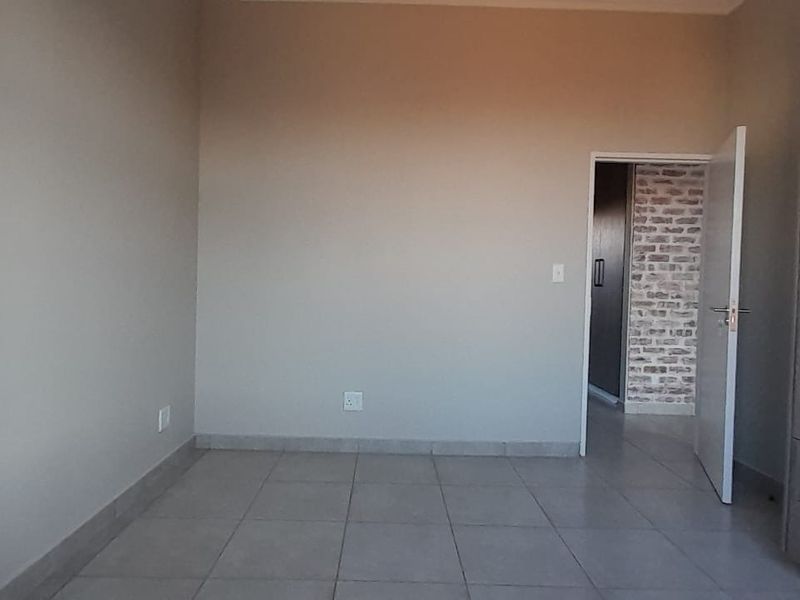 A clean, empty bedroom featuring neutral tiled flooring and modern built-in cupboards, offering a blank canvas for personalization.