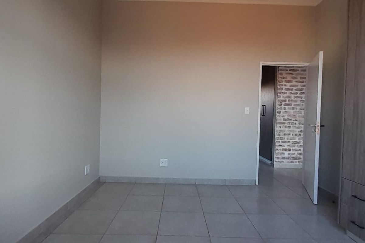 A clean, empty bedroom featuring neutral tiled flooring and modern built-in cupboards, offering a blank canvas for personalization.