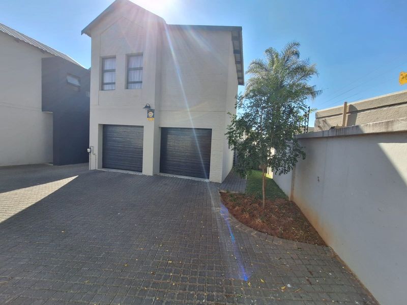 Front elevation of a modern double-story home featuring a paved driveway, double garage, and secure boundary wall.