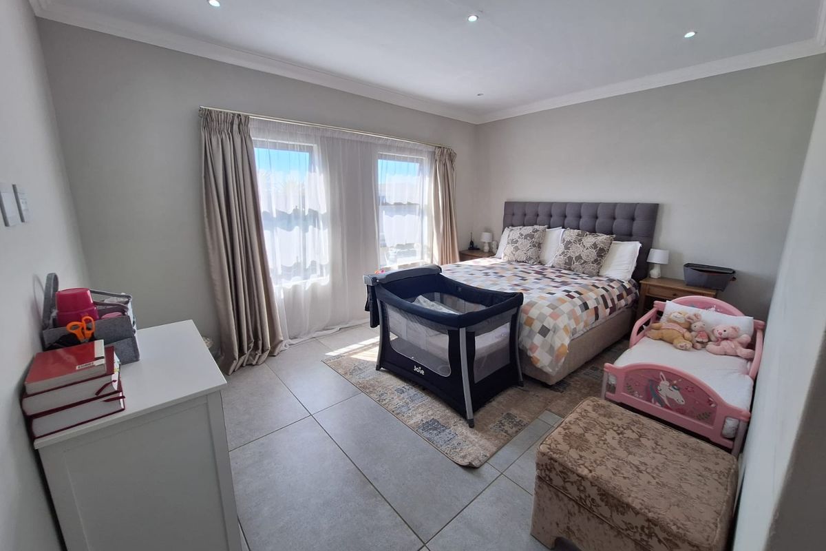 A well-maintained bedroom featuring neutral wall tones, large windows with curtain treatments, tiled flooring, and recessed ceiling lighting.