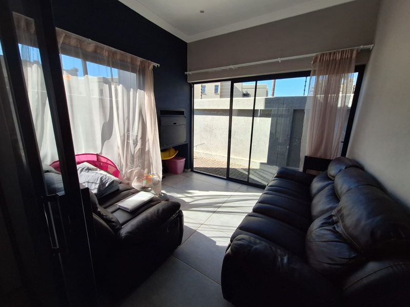 A bright living room featuring large sliding glass doors that provide direct access to the outdoor area, complemented by neutral tiled flooring.