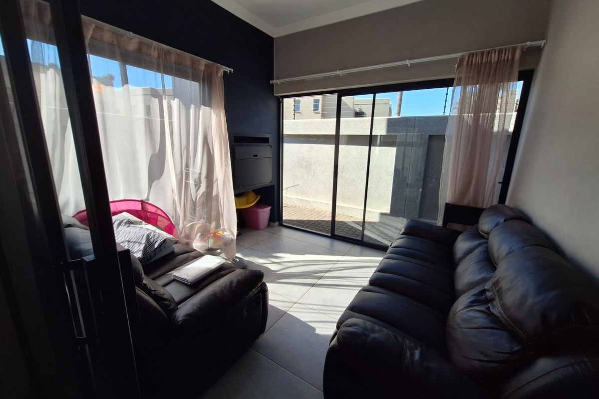 A bright living room featuring large sliding glass doors that provide direct access to the outdoor area, complemented by neutral tiled flooring.