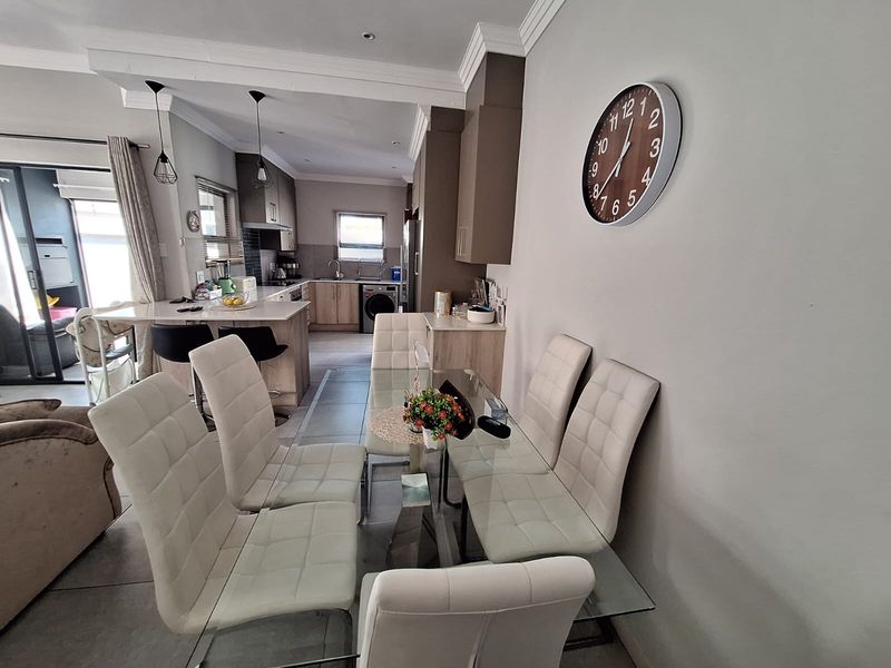 An open-plan living and dining area featuring a modern kitchen with stone countertops, breakfast bar, and tiled flooring throughout.