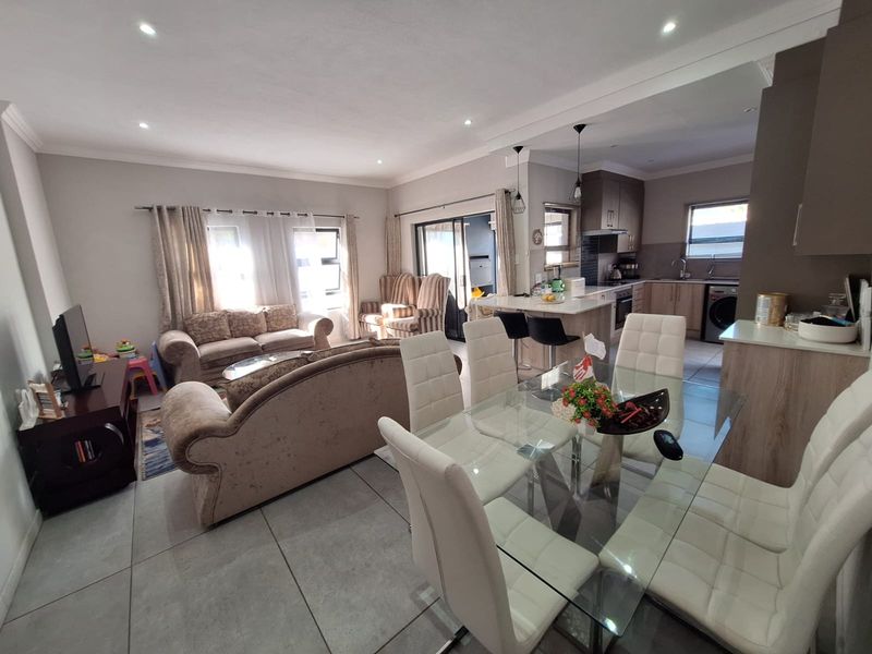 Spacious open-plan living, dining, and kitchen area featuring modern tiled floors, recessed lighting, and a functional kitchen island with integrated cabinetry.